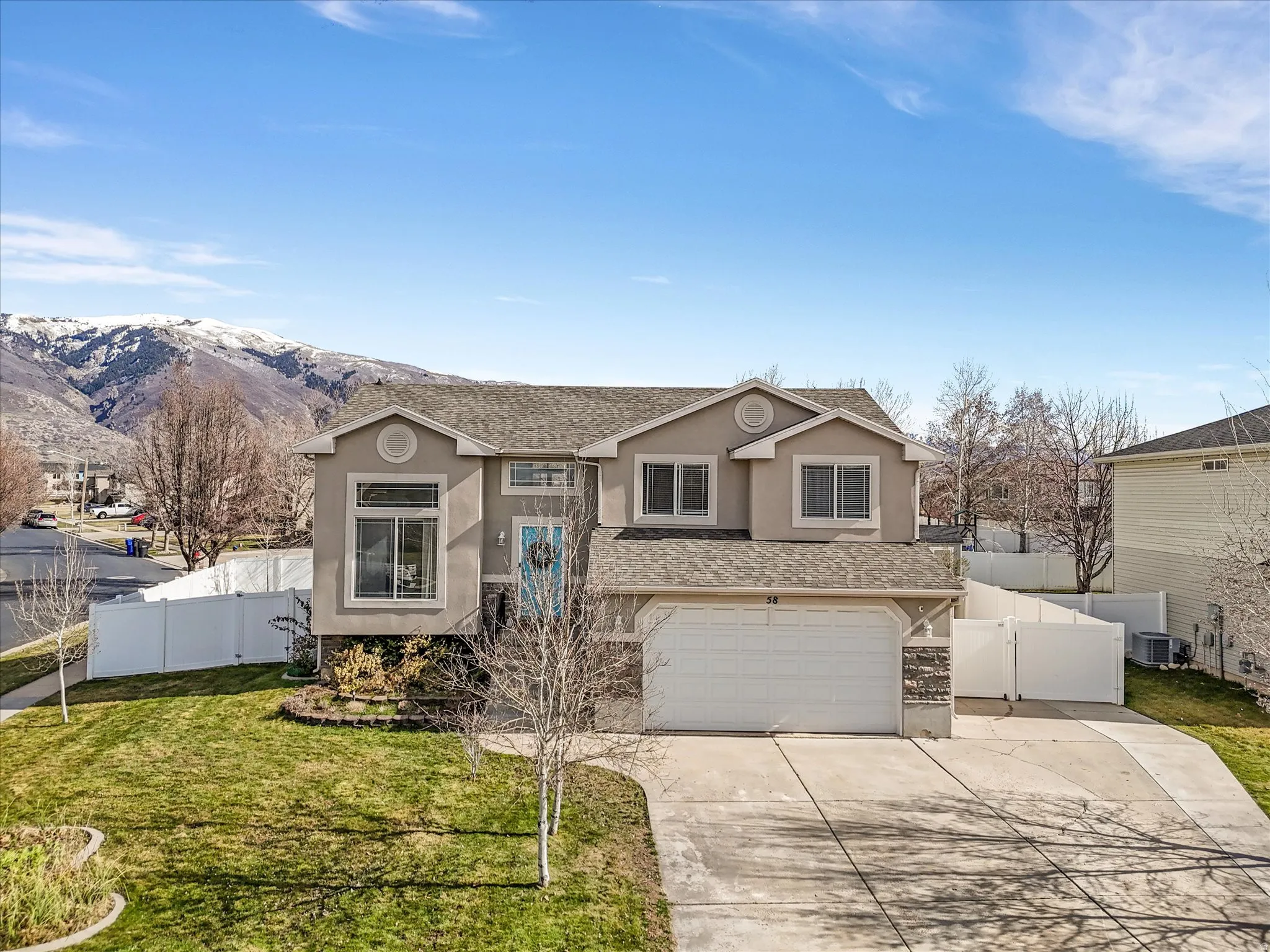 View of front facade featuring a gate, stucco siding, driveway, a garage, and a shingled roof