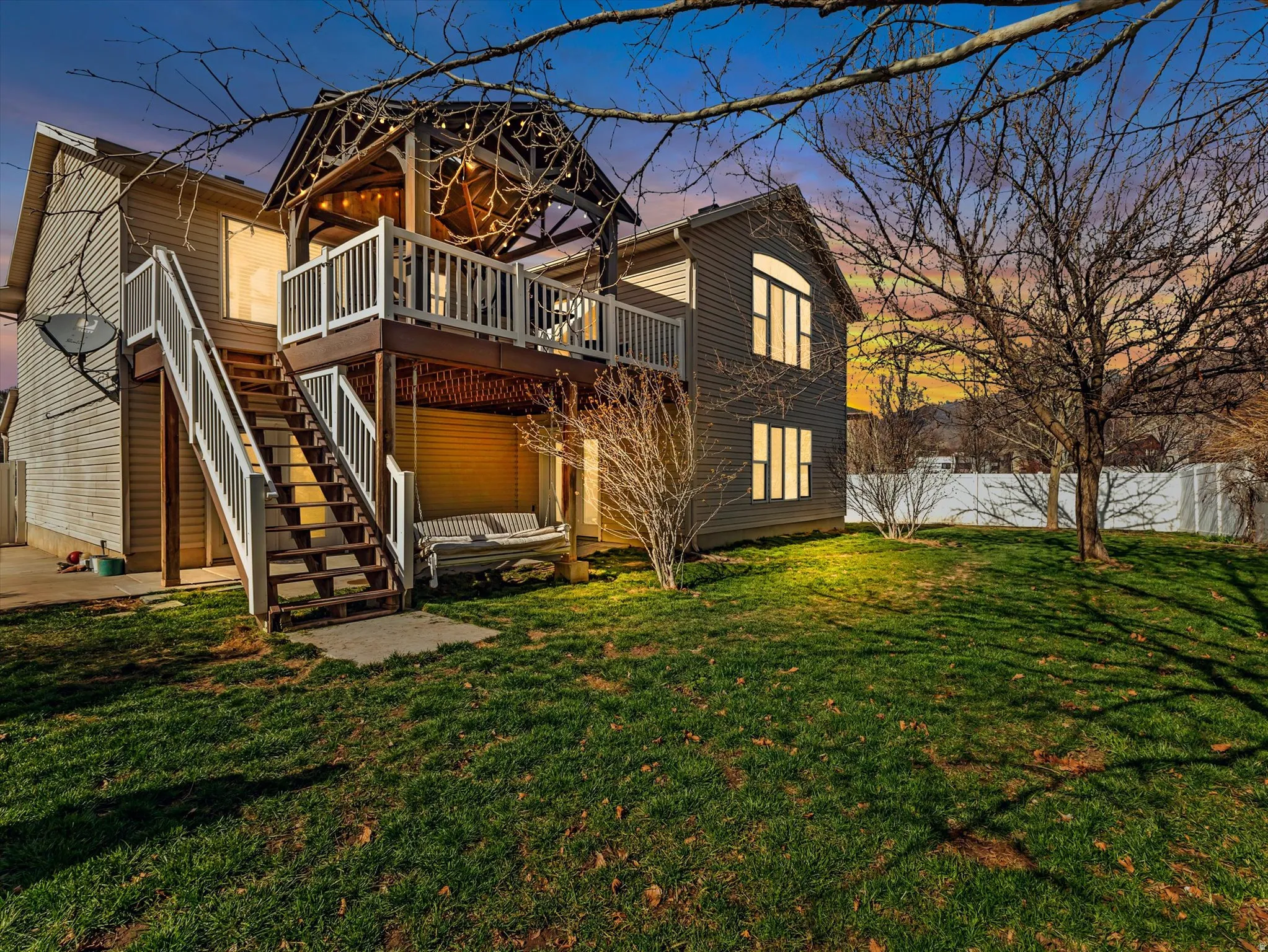Backyard featuring a multi-level deck with white railings, direct stair access to the yard, and a covered upper patio