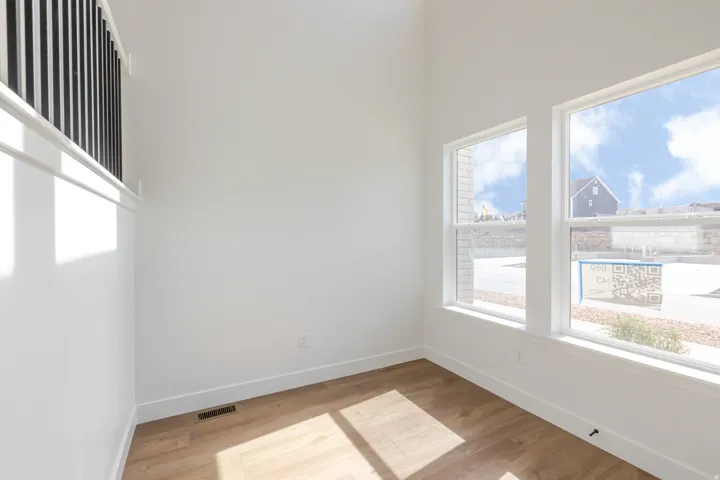Bright interior space featuring wood-finish flooring, white walls, and tall windows