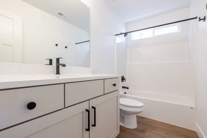 Bathroom featuring a white vanity with matte black hardware, a rectangular undermount sink, a white countertop, and wood-finish flooring