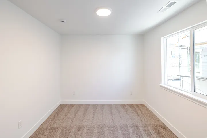 Interior room featuring a large window, neutral wall paint, and plush carpeting