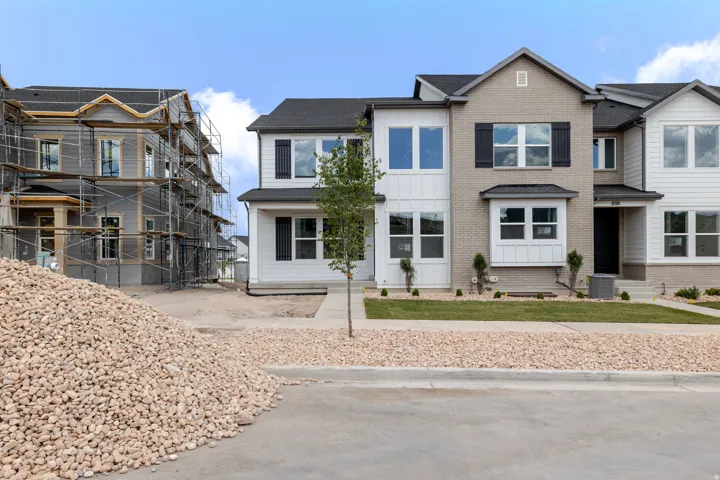 Modern townhome exterior featuring light brick and white vertical siding