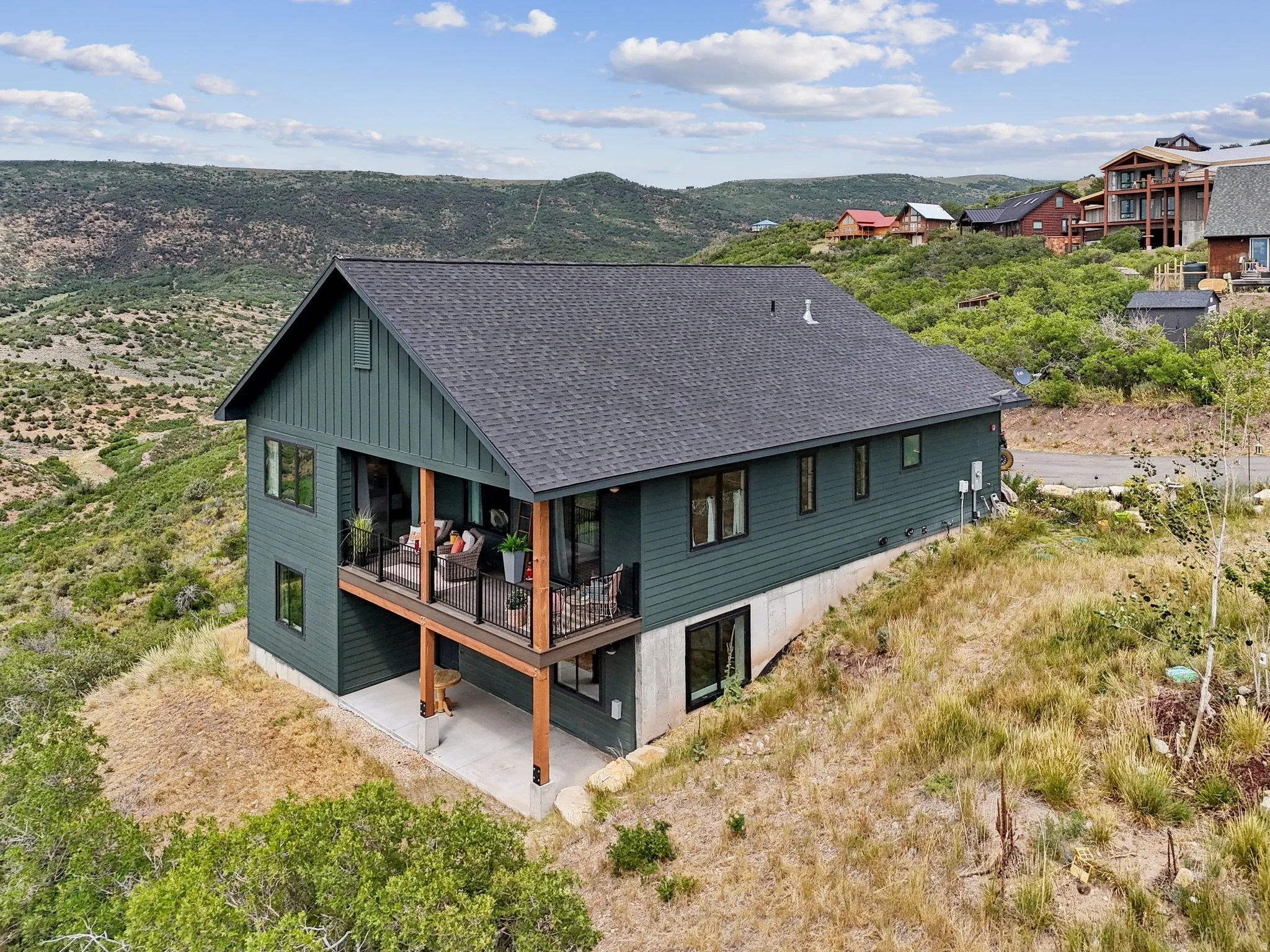 Back of property featuring a shingled roof, a mountain view, and a patio