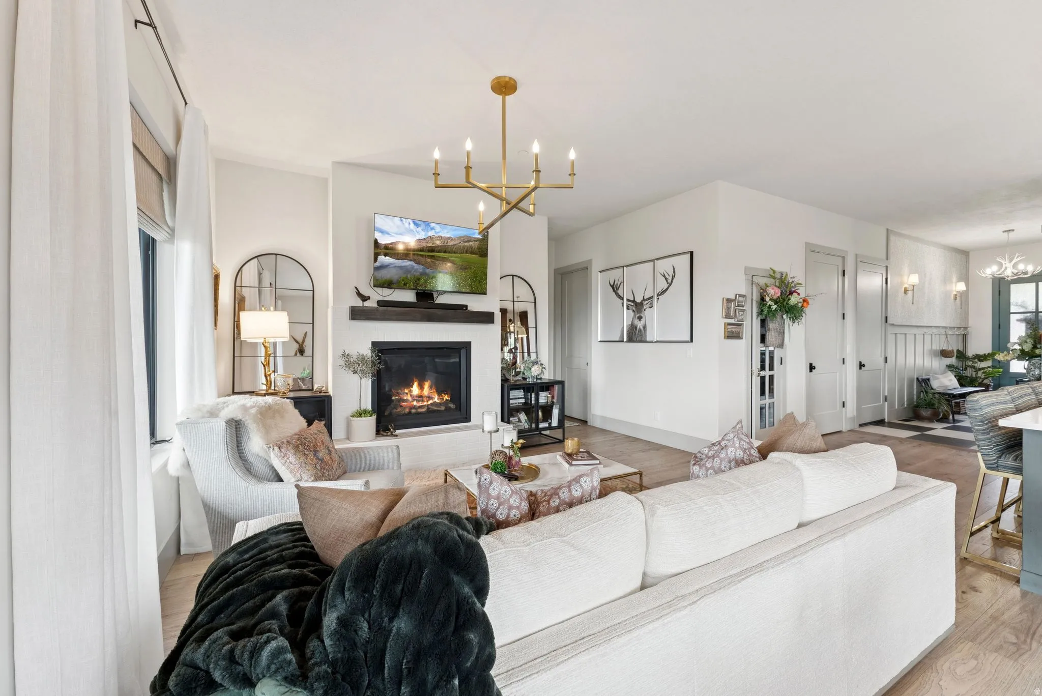 Living room with hanging lights, a glass covered fireplace, and light wood-style flooring