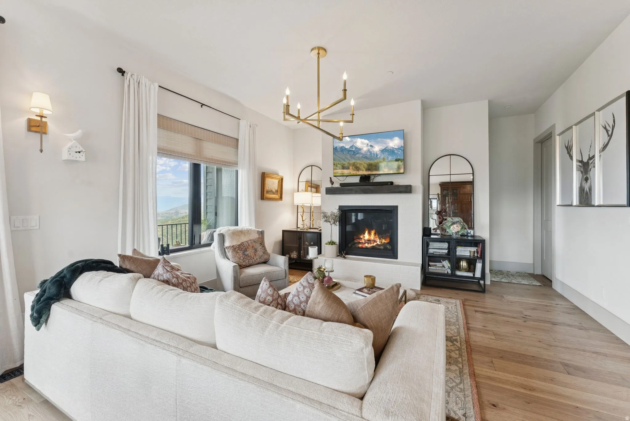 Living area featuring a glass covered fireplace, light wood finished floors, and suspended lighting
