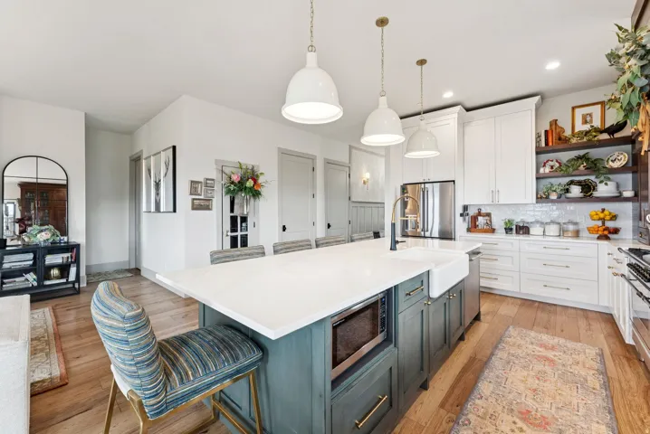 Two tone kitchen with a breakfast bar area, two tone cabinets, pendant lighting, light wood finished floors, and a center island with sink