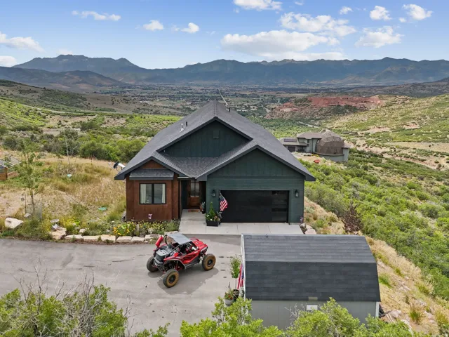 View of front of home with a mountain view, concrete driveway, a garage, and roof with shingles