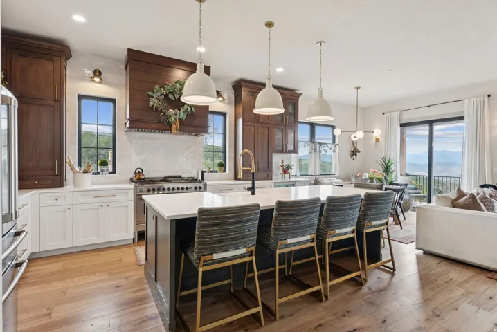 Two tone kitchen with a kitchen breakfast bar, an island with sink, light wood-style floors, tasteful backsplash, and dual tone cabinetry
