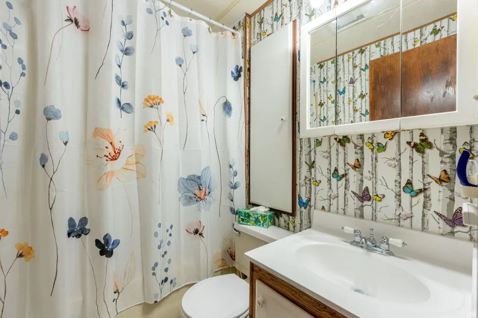 Bathroom featuring wallpapered walls and vanity