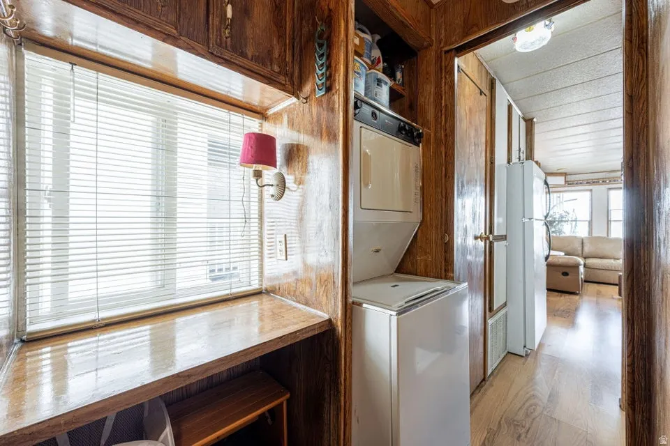 Laundry area with light wood-style flooring and stacked washer and dryer