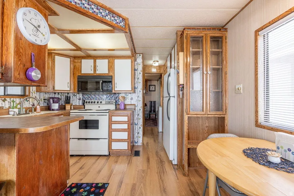 Kitchen featuring white appliances, light wood-style floors, plenty of natural light, two tone cabinetry, and a peninsula
