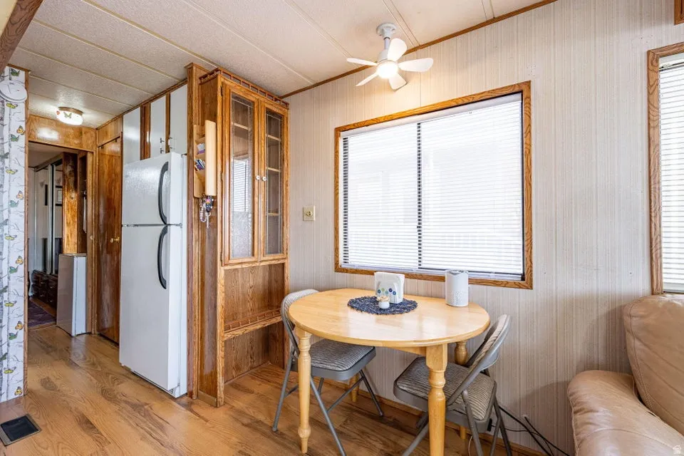 Dining space with light wood-type flooring, ceiling fan, and ornamental molding