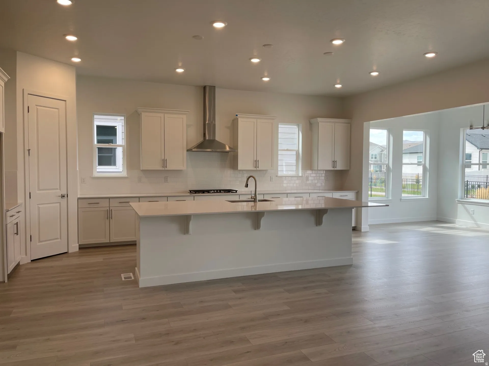 Kitchen featuring a kitchen breakfast bar, tasteful backsplash, an island with sink, white cabinets, and recessed lighting