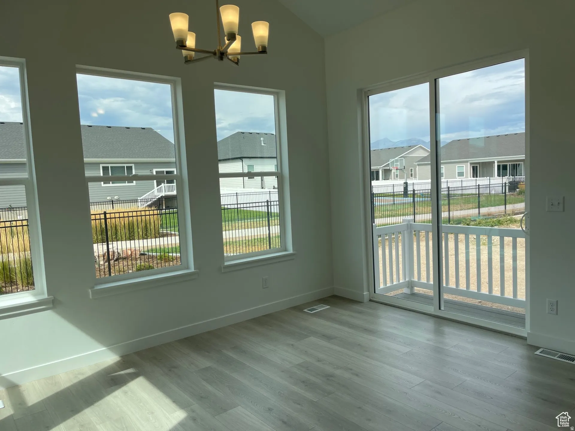 Unfurnished dining area with a residential view, wood finished floors, a chandelier, and vaulted ceiling