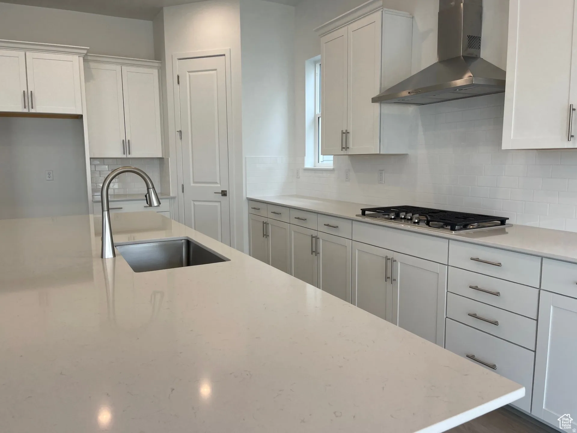 Kitchen featuring white cabinetry, decorative backsplash, and light stone countertops