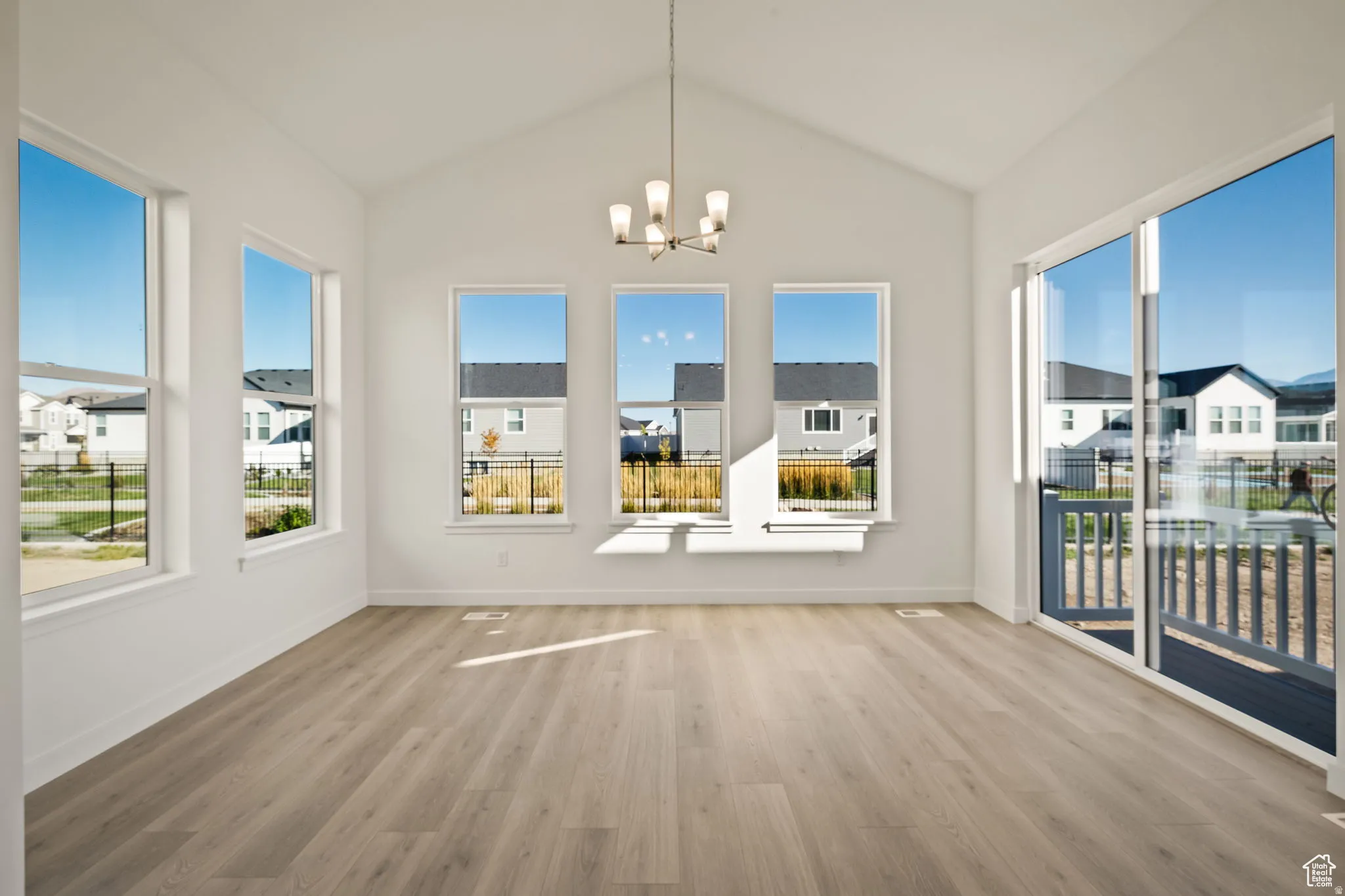 Unfurnished dining area featuring a chandelier, light wood-style flooring, and a residential view