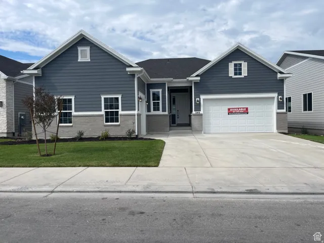 Single story home with brick siding, driveway, and a front yard