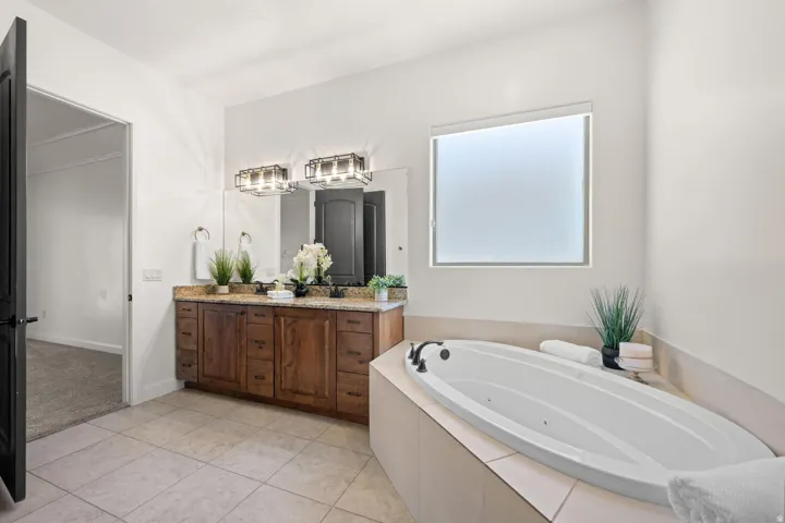 Full bathroom featuring double vanity, a jetted tub, and light tile patterned floors