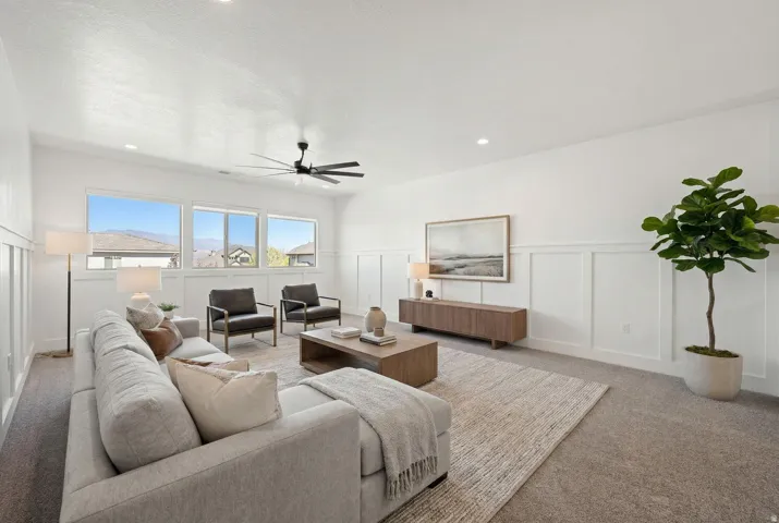 Living room featuring a decorative wall, a wainscoted wall, light carpet, ceiling fan, and recessed lighting