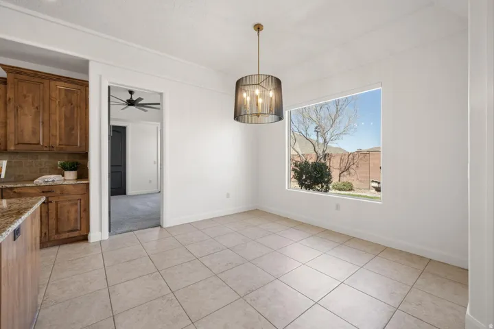 Unfurnished dining area featuring a chandelier, light tile patterned floors, and a ceiling fan