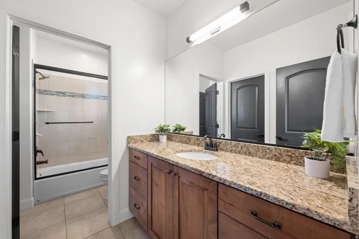 Full bathroom with vanity, enclosed tub / shower combo, and light tile patterned floors