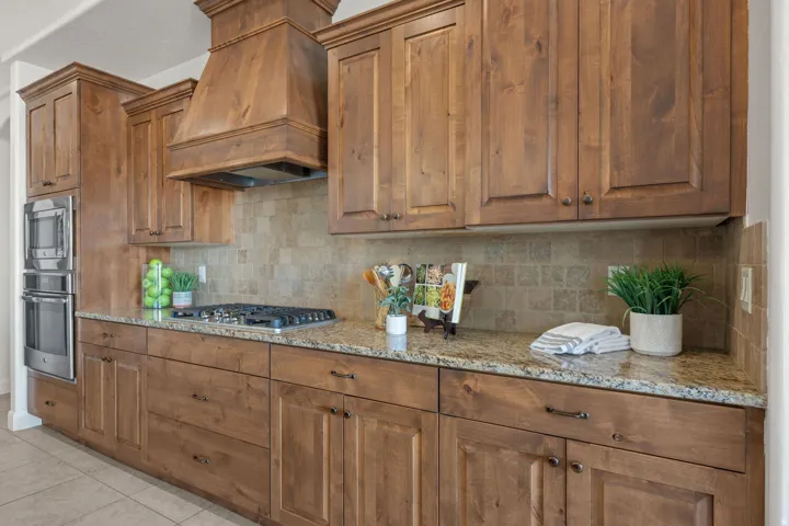 Kitchen with light stone countertops, wood finish cabinetry, stainless steel appliances, and light tile patterned flooring