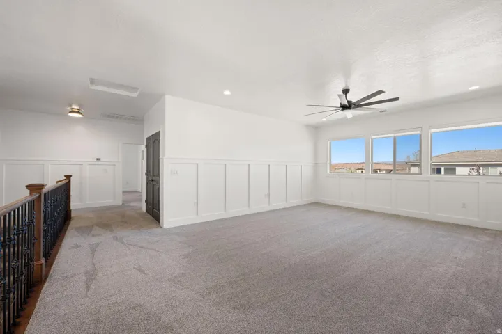 Spare room featuring a decorative wall, a wainscoted wall, light colored carpet, a ceiling fan, and recessed lighting