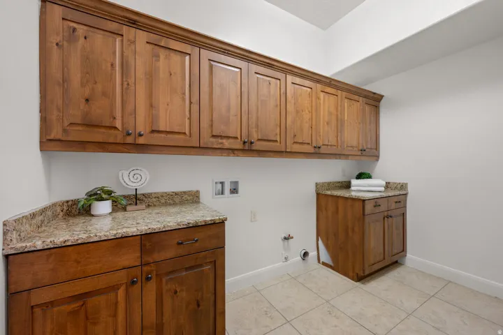 Laundry area with gas dryer hookup, washer hookup, light tile patterned floors, and cabinet space