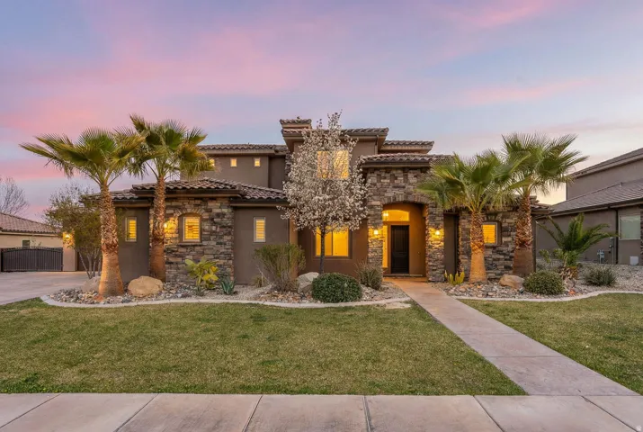 Mediterranean / spanish house featuring stone siding, a lawn, stucco siding, and a tile roof