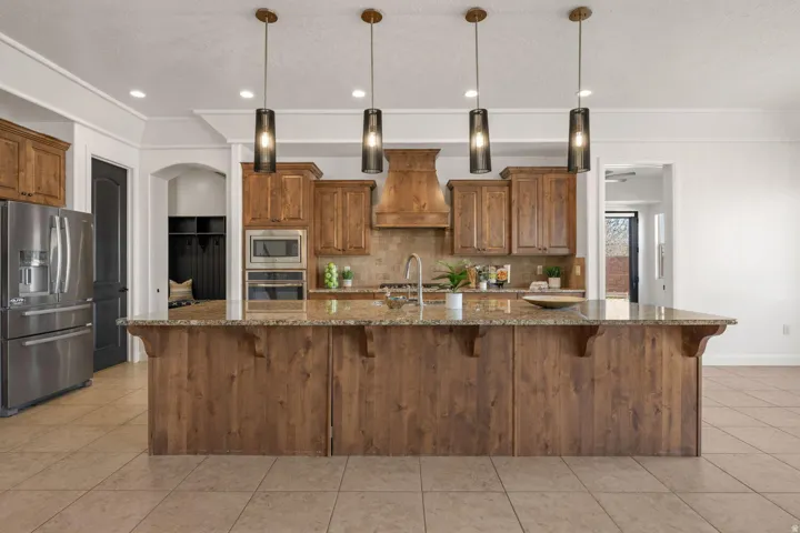 Kitchen with wood finish cabinets, stainless steel appliances, a kitchen breakfast bar, dark stone counters, and crown molding
