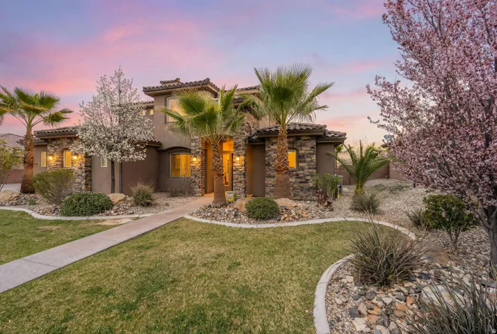Mediterranean / spanish-style house featuring a front lawn, a tile roof, stucco siding, and stone siding