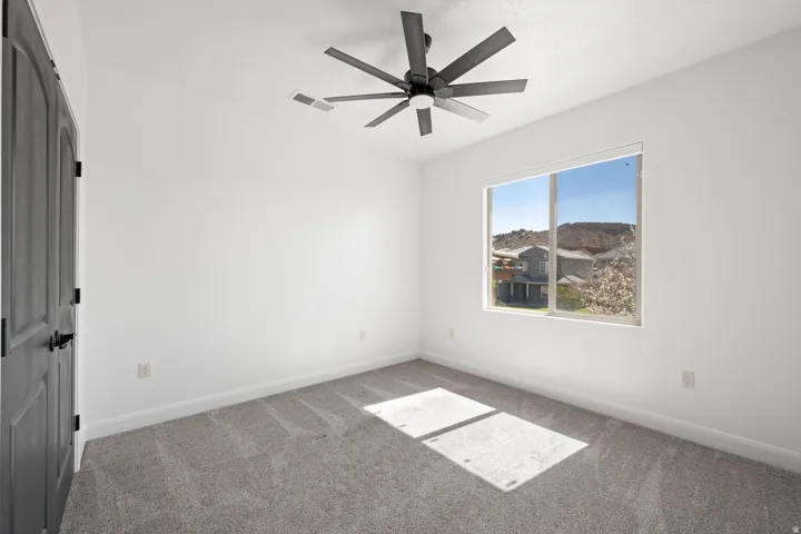 Carpeted empty room featuring baseboards and a ceiling fan