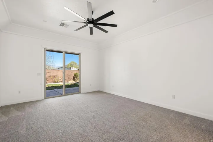 Carpeted spare room with ceiling fan and ornamental molding