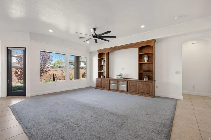 Unfurnished living room with arched walkways, ceiling fan, light tile patterned floors, recessed lighting, and a textured ceiling