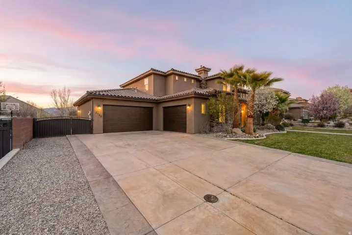 Mediterranean / spanish-style house with stucco siding, an attached garage, driveway, a gate, and a tiled roof
