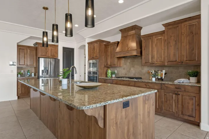 Kitchen with a breakfast bar, light stone counters, light tile patterned flooring, and a center island with sink