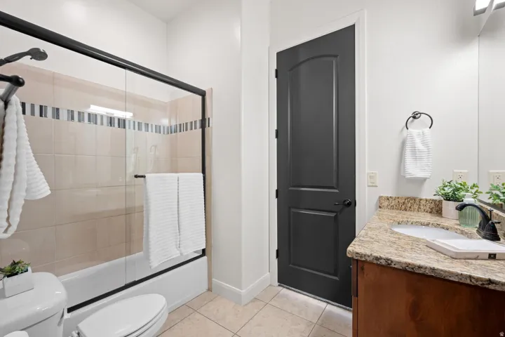 Bathroom featuring vanity, shower / bath combination with glass door, and light tile patterned floors