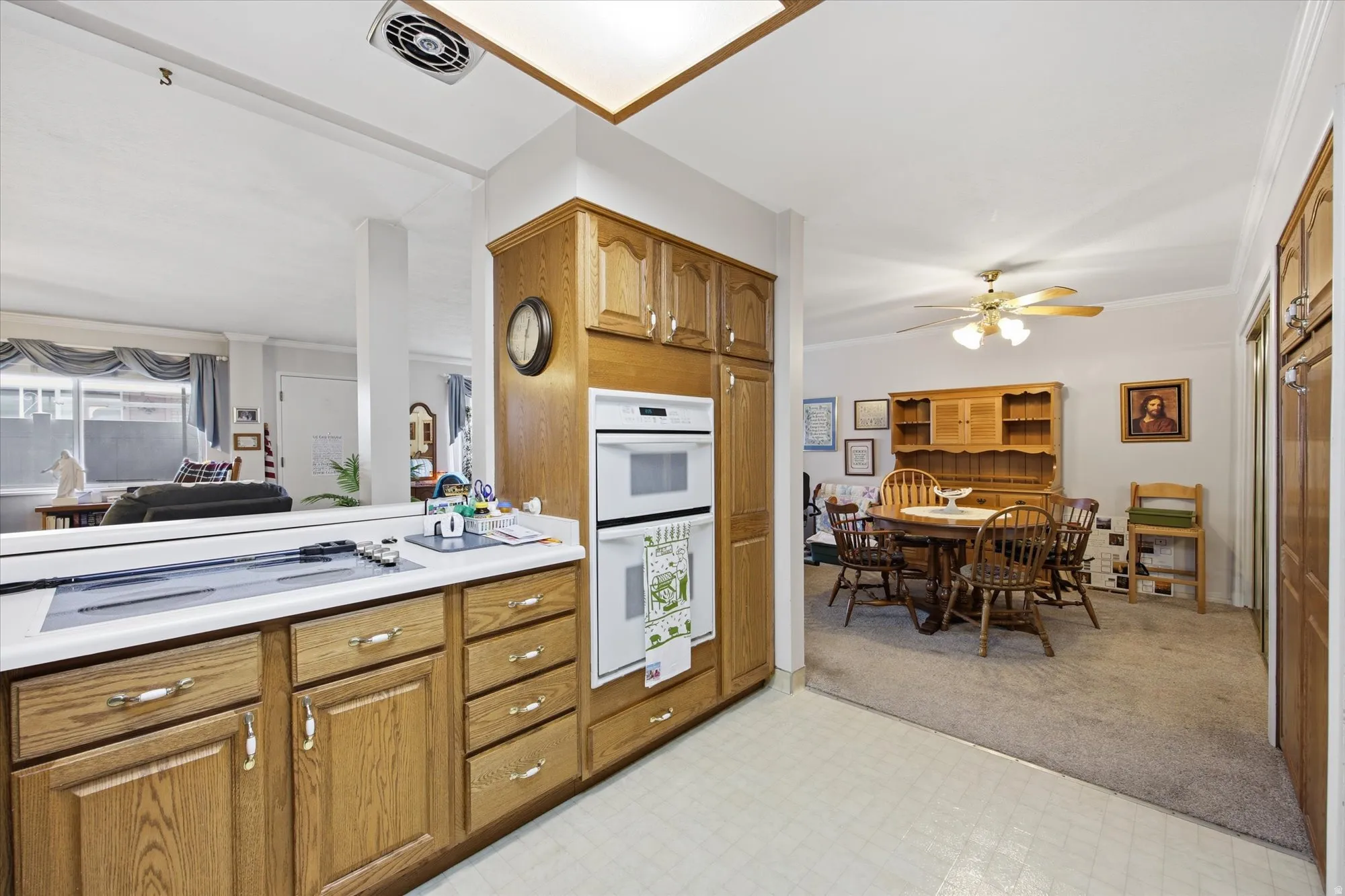 Kitchen with light floors, light countertops, white appliances, crown molding, and wood finish cabinets