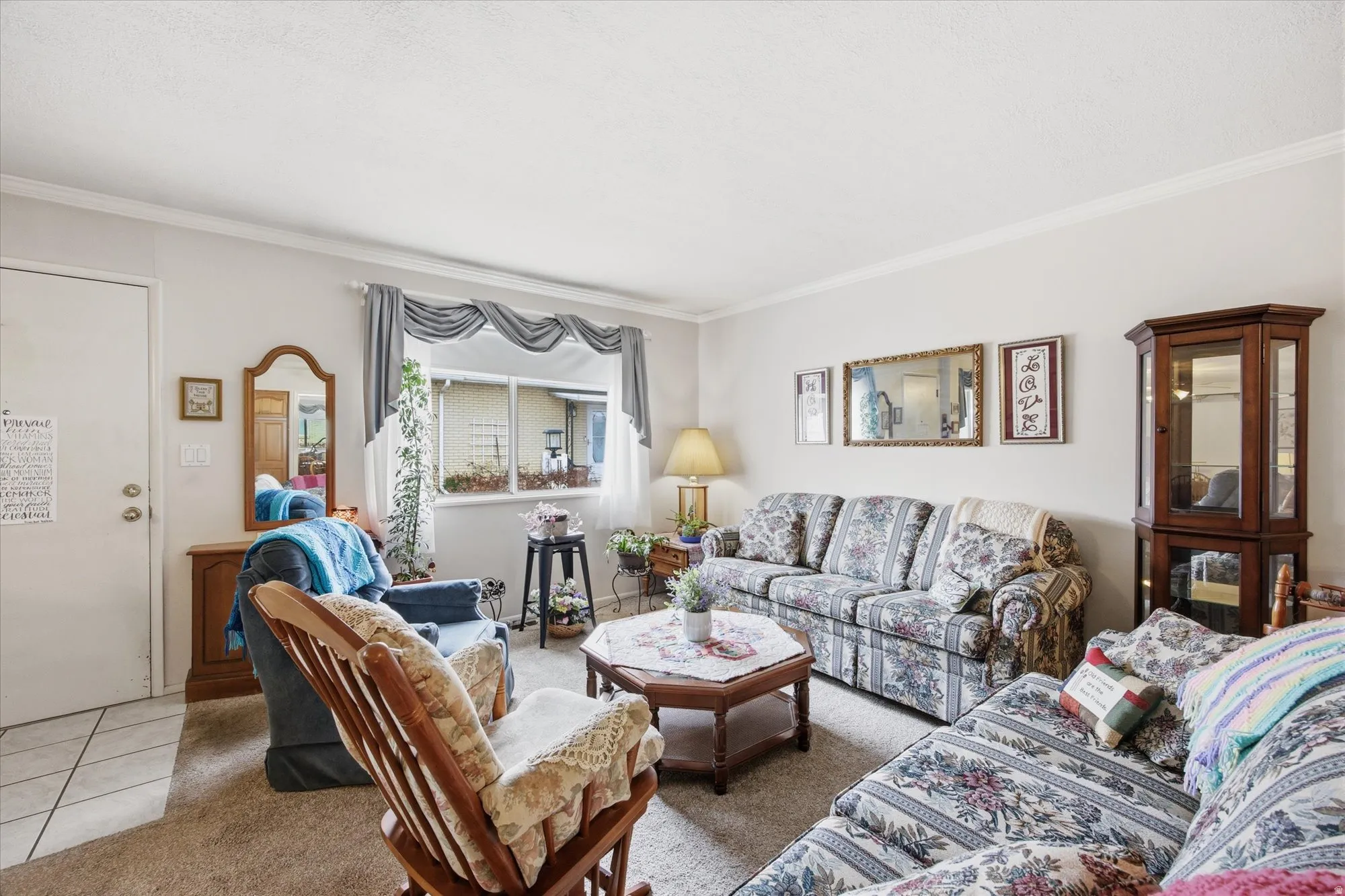 Carpeted living room featuring crown molding and tile patterned floors