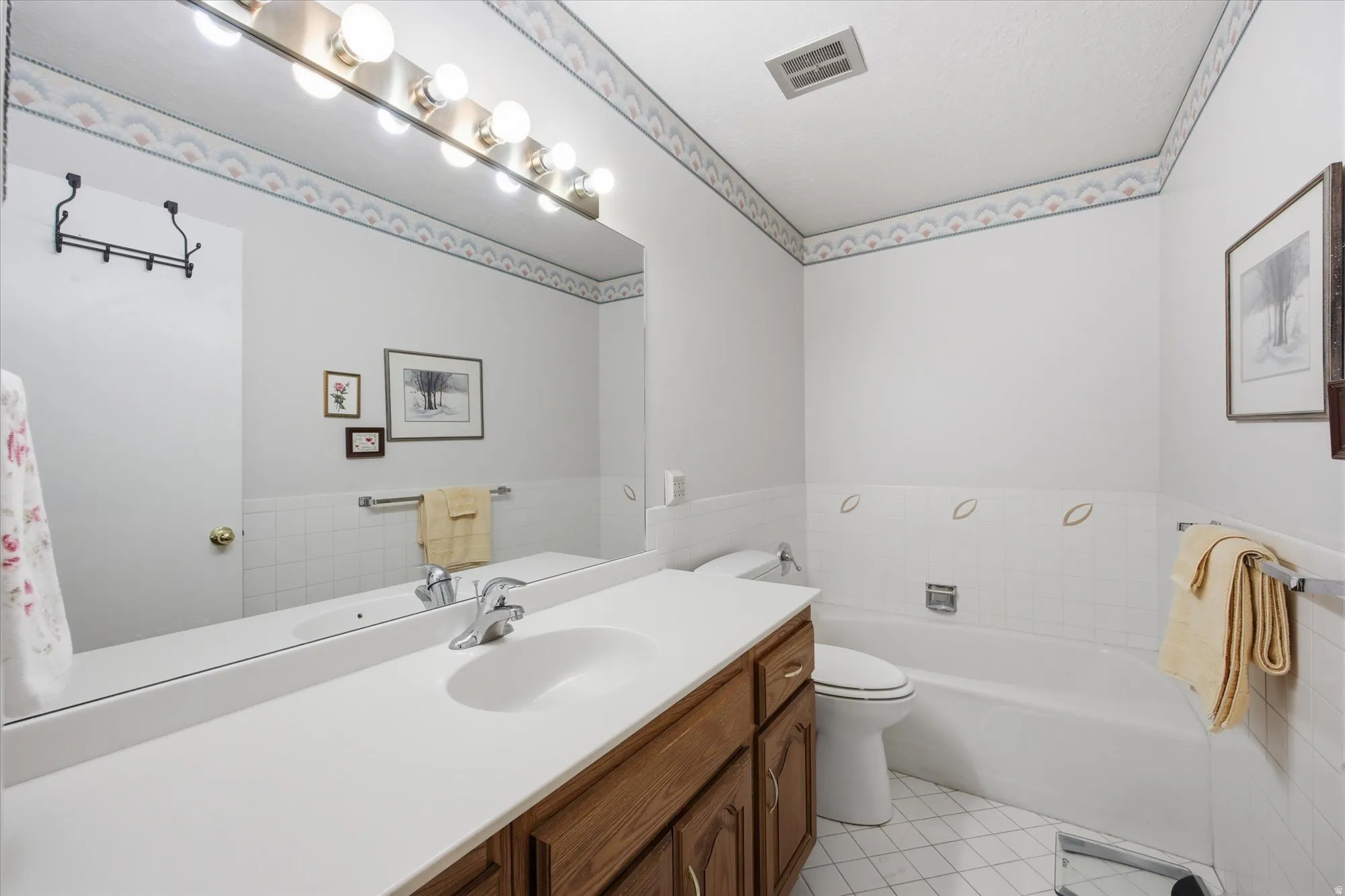 Full bath with vanity, a bath, and light tile patterned floors