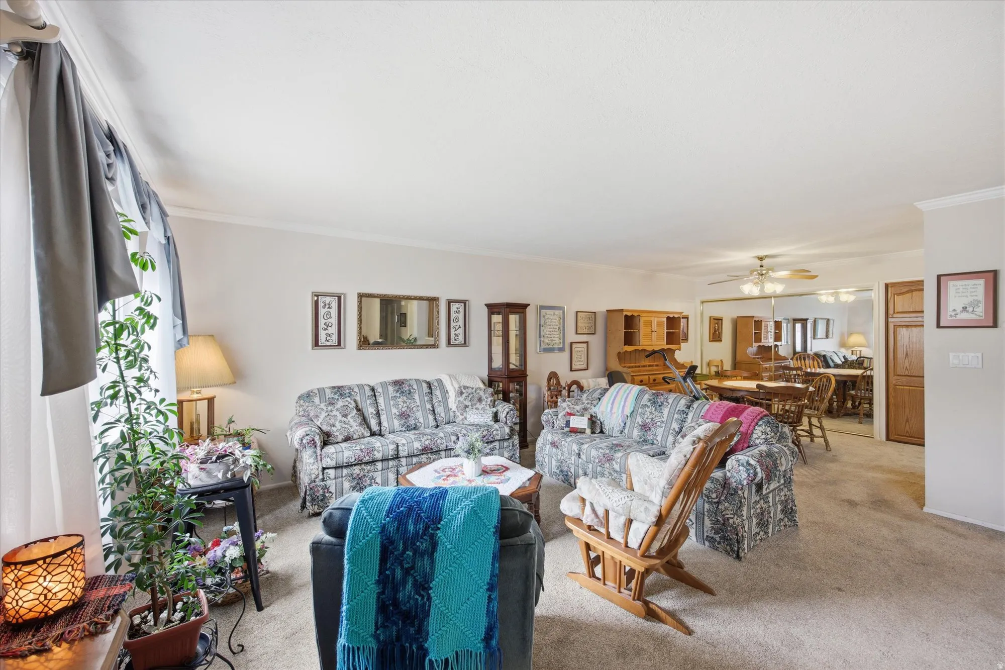 Living room featuring crown molding, light carpet, and ceiling fan