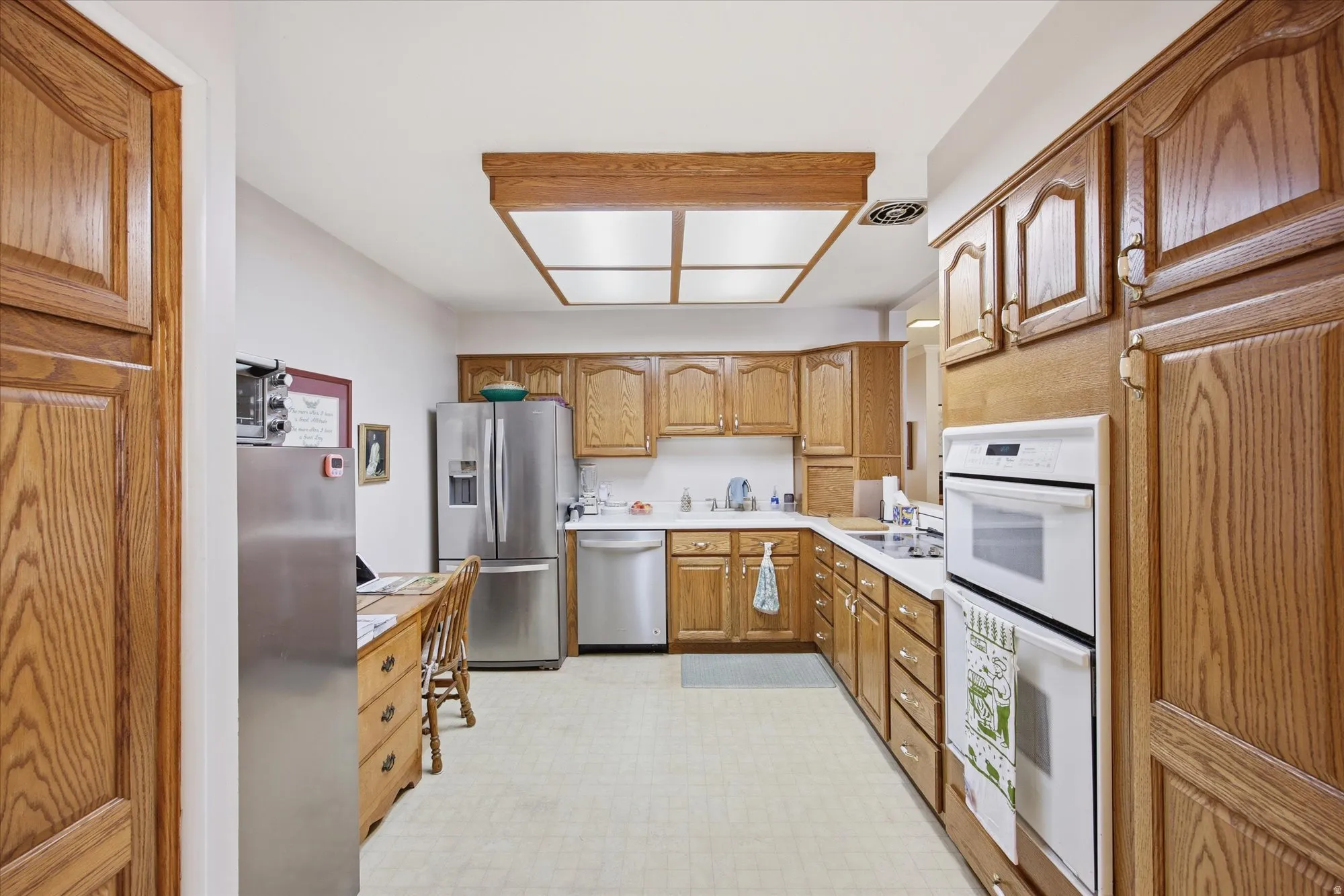 Kitchen with light countertops, stainless steel appliances, light floors, and wood finish cabinetry