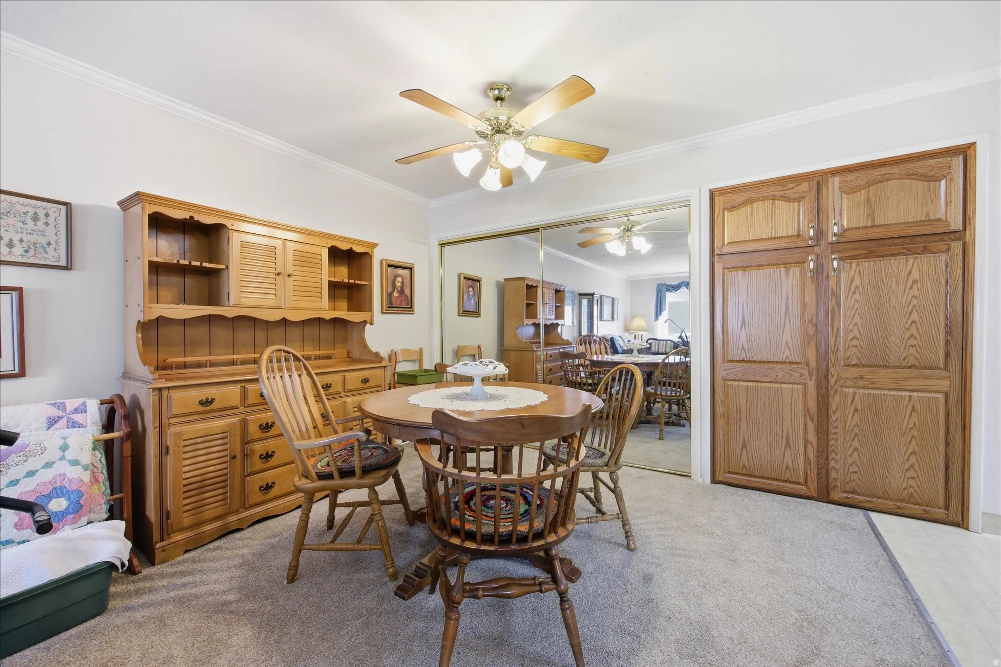 Carpeted dining space featuring crown molding and ceiling fan