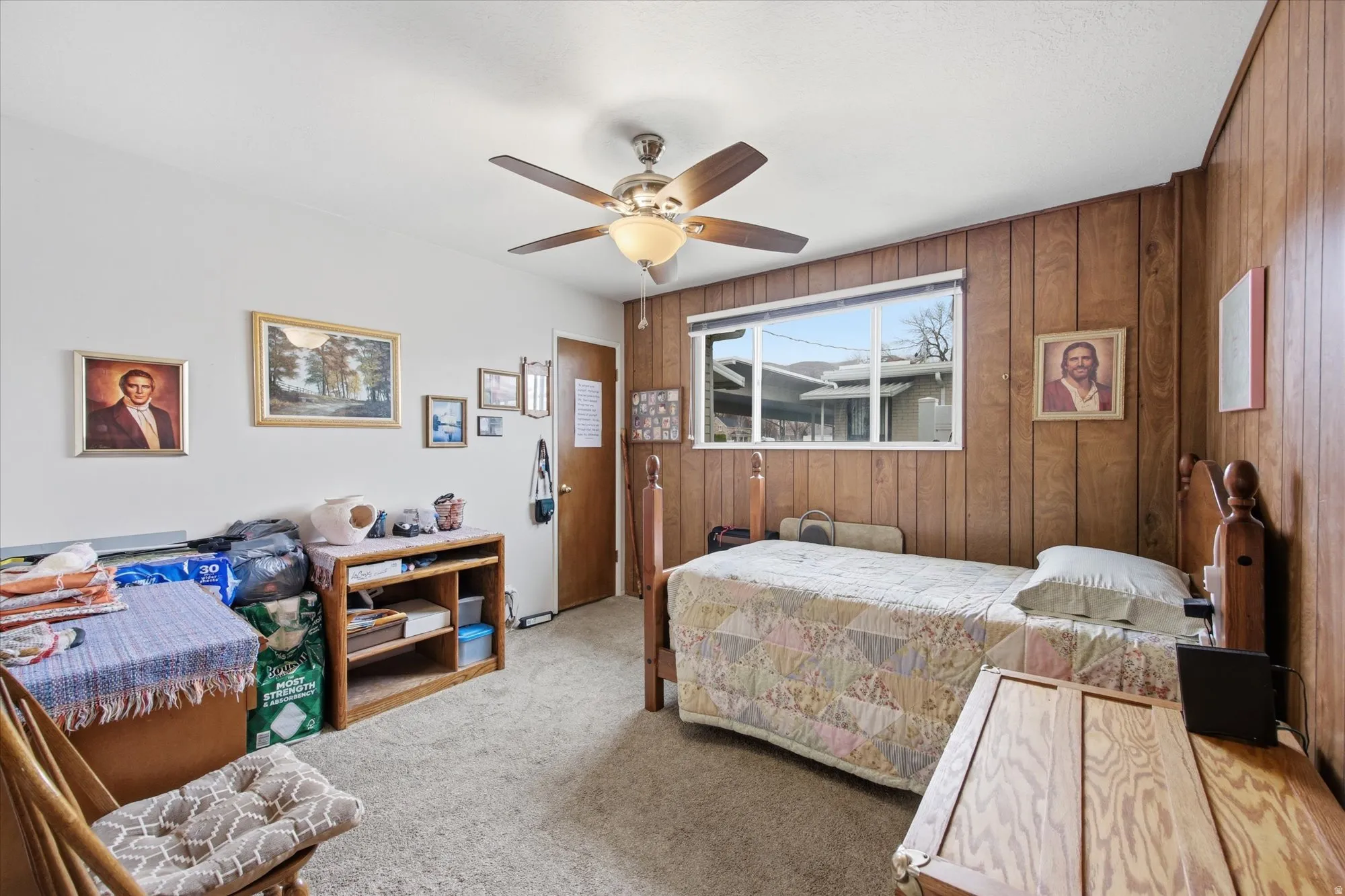 Carpeted bedroom with wood walls and a ceiling fan