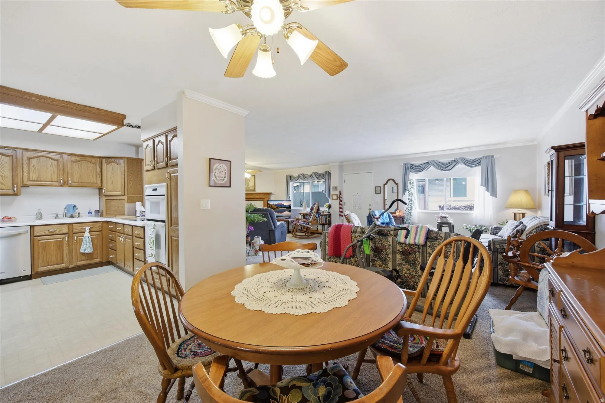 Dining space featuring ornamental molding, a ceiling fan, light flooring, and light carpet