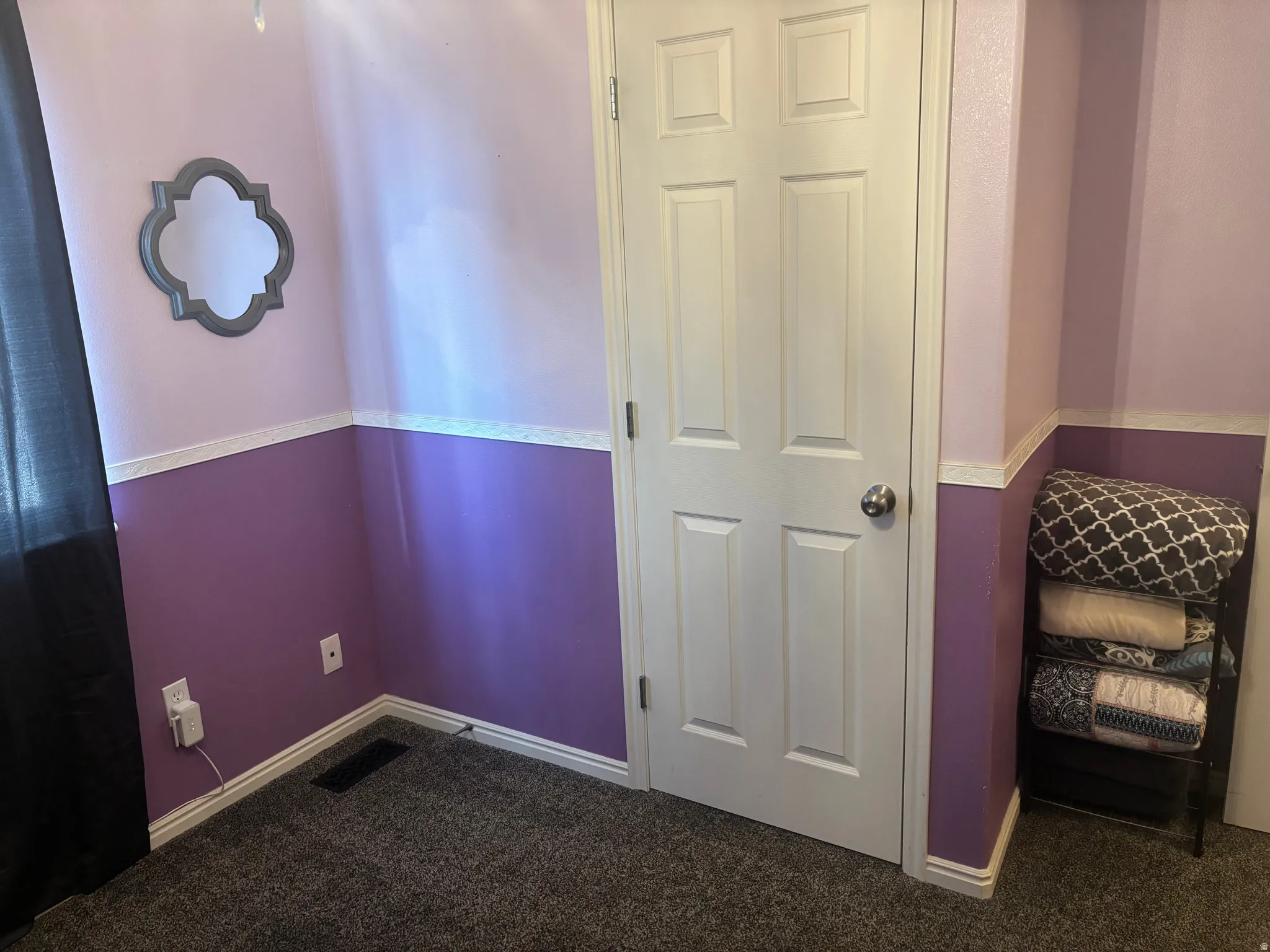 Unfurnished bedroom with dark colored carpet and baseboards