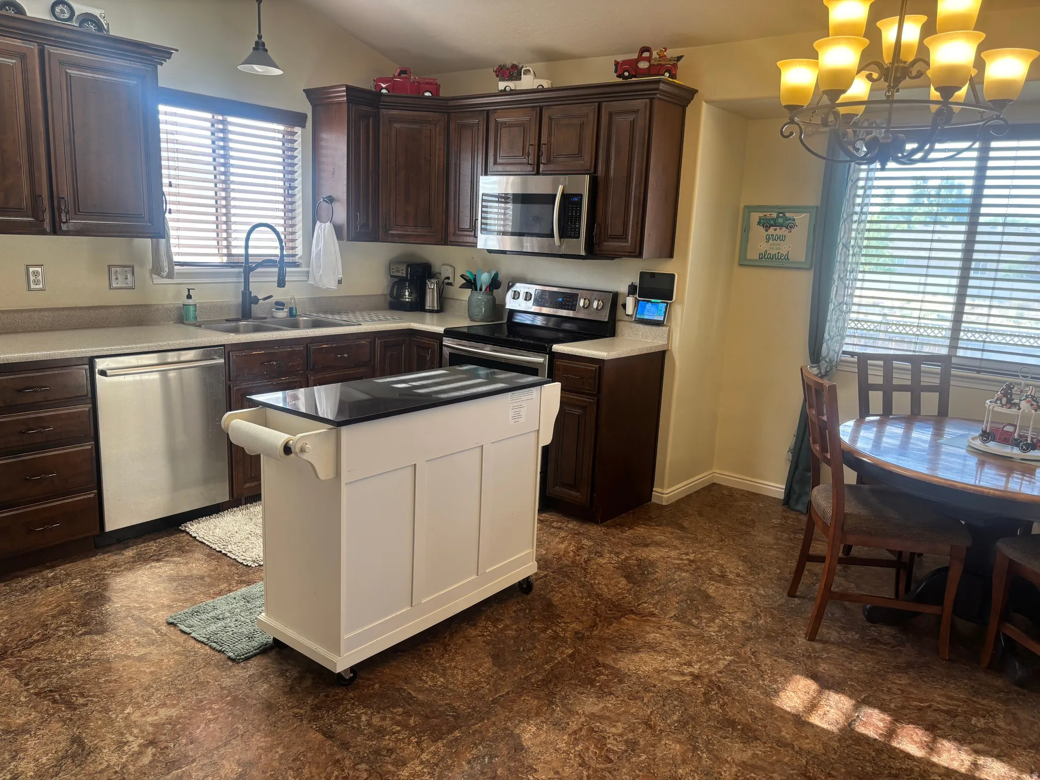 Kitchen with stainless steel appliances, hanging lights, vaulted ceiling, a kitchen island, and dark stone countertops