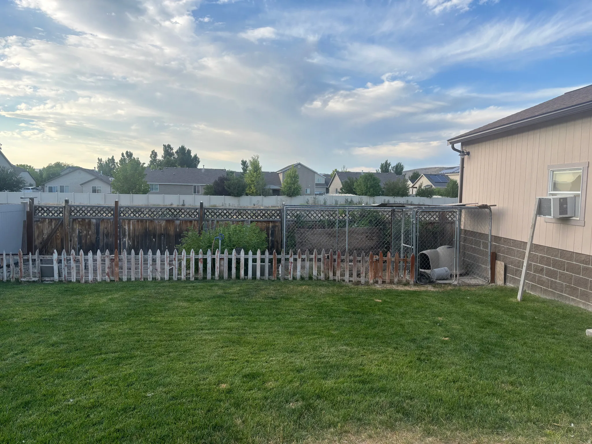 Fenced backyard featuring a residential view and cooling unit
