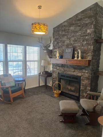 Living area with a fireplace, lofted ceiling, and dark colored carpet