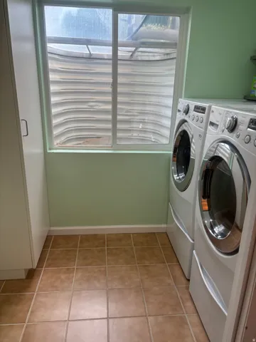 Laundry area featuring washing machine and clothes dryer and light tile patterned floors